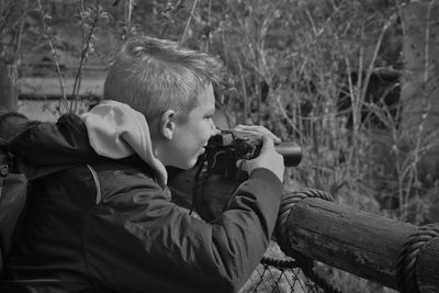 Close-up of boy photographing through camera in forest