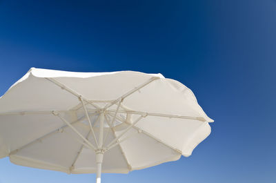 Low angle view of white umbrella against blue sky
