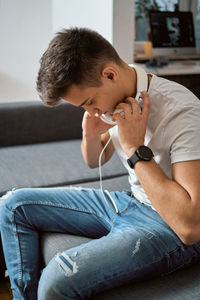 Man with headphones sitting on sofa at home