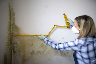 Portrait of young woman standing against wall