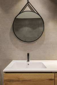 Modern bathroom with white sink, wooden base and round mirror. minimalist interior in warm colors