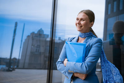 Business woman with folder in hand near office building