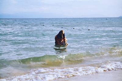 People in sea against sky