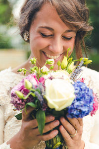 Close-up of smiling bride with bouquet outdoors