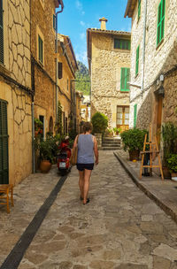 Rear view of woman walking on street amidst buildings