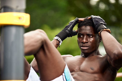 Side view of shirtless man exercising at park