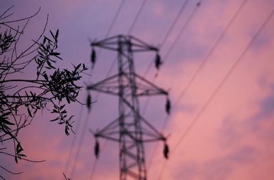 Low angle view of silhouette electricity pylon against romantic sky