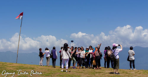 People standing on field against sky