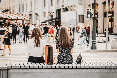 Rear view of people walking on sidewalk in city