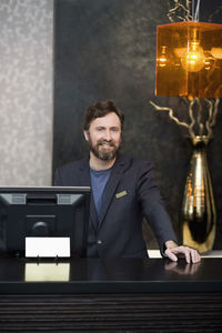 Portrait of smiling male receptionist standing at counter in hotel
