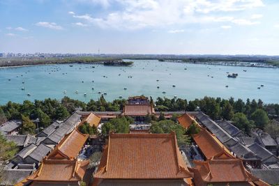 Kunming lake and buildings against sky seen through summer palace in city