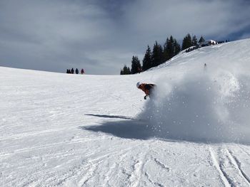 Teenage boy skiing on snow covered landscape against sky