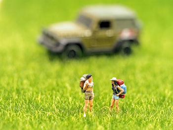 Close-up of figurines by toy car on grass