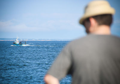 Rear view of man sailing on sea against sky