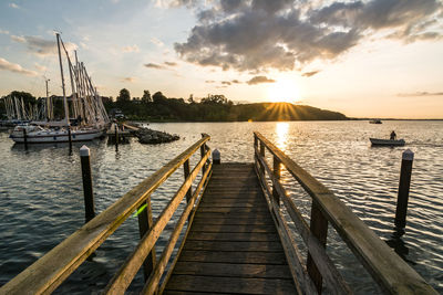 Pier over sea against sky during sunset