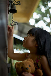 Low angle view of girl holding teddy bear standing at entrance