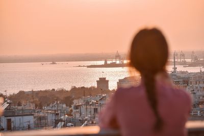 Rear view of woman looking at cityscape against sky