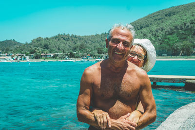 Portrait of couple smiling while standing at beach against mountain