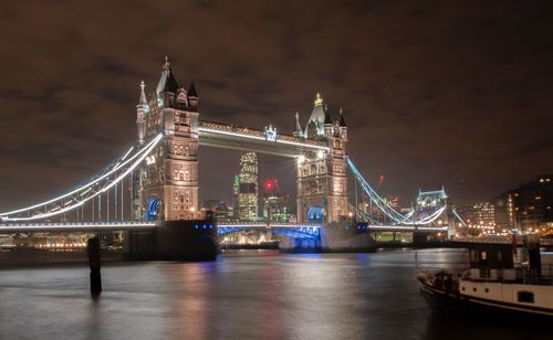 Illuminated suspension bridge over river at night