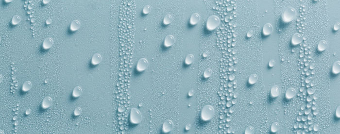 Full frame shot of raindrops on blue glass