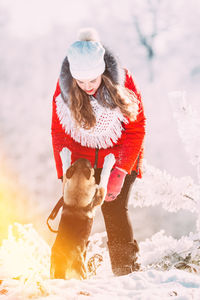 Rear view of woman with dog on snow covered field