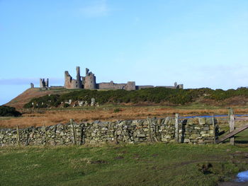 House on field against clear blue sky