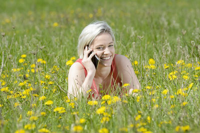 Portrait of smiling young woman using mobile phone in field