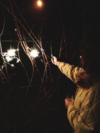 Midsection of man with fire crackers at night
