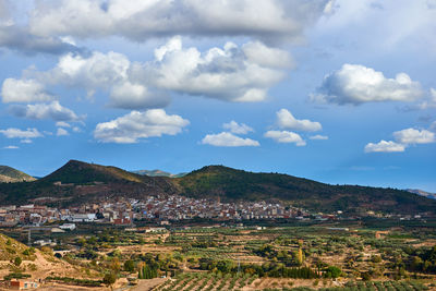 Scenic view of town by mountains against sky