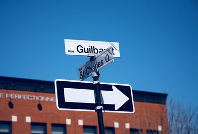 Low angle view of road sign against clear blue sky