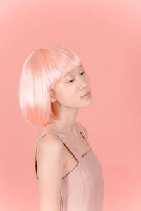 Close-up of young woman against pink background