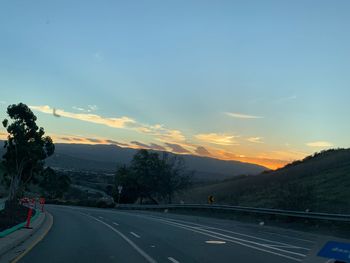 Road by trees against sky