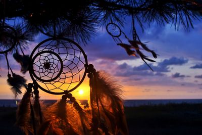 Close-up of dreamcatcher against sky during sunset