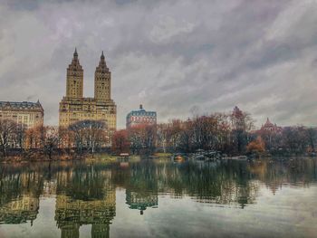 Reflection of buildings in lake against cloudy sky
