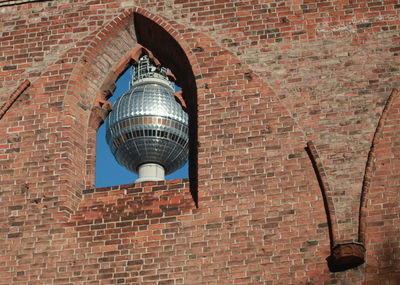 Low angle view of electric lamp against brick wall