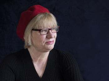 Mature woman with red cap against black background