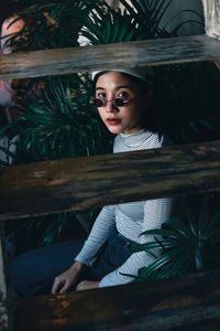 Portrait of young woman sitting by tree
