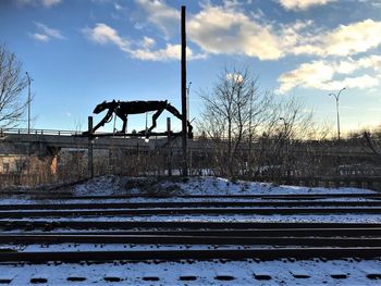 Railroad tracks on snow covered field against sky