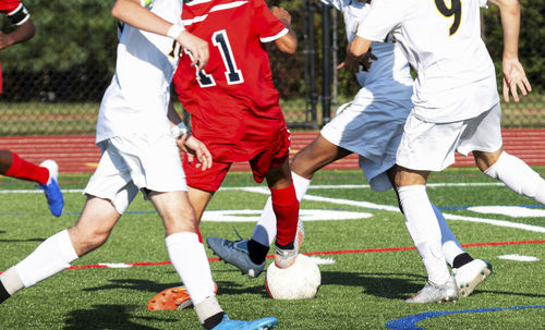 Low section of people playing soccer on field