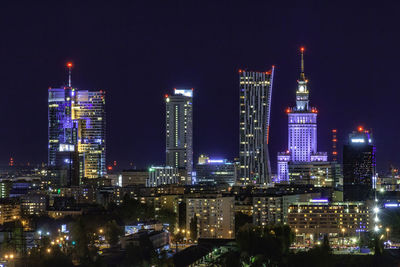 Illuminated buildings in city against sky at night