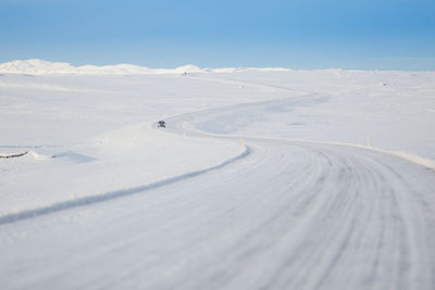 Car on snow covered road against sky