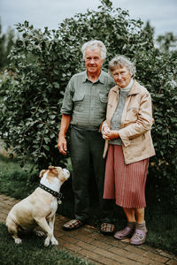 Portrait of people with dog against plants