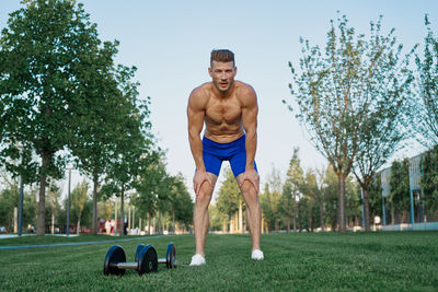 Portrait of shirtless man exercising on field