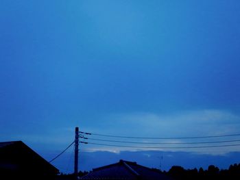 Low angle view of silhouette buildings against blue sky