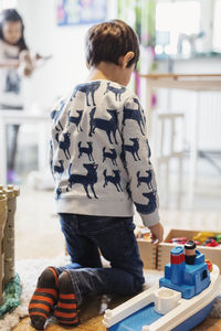 Rear view of boy playing with toys at preschool