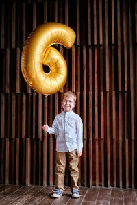 Portrait of boy holding 6 number balloon