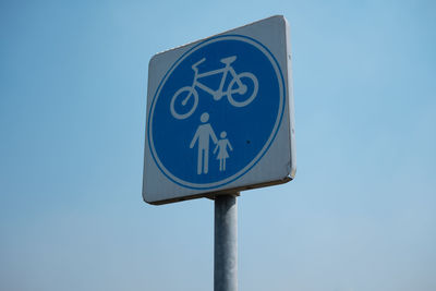 Low angle view of road sign against clear blue sky