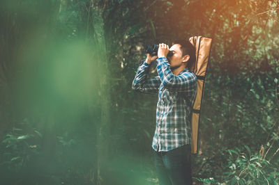 Man with binoculars telescope in forest looking destination