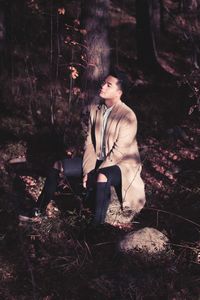 Young woman sitting on tree trunk in forest