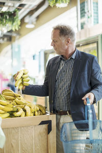 Mature man examining bananas in organic supermarket